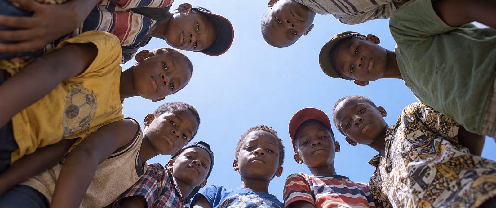 A group of children looking down toward the camera under a clear sky